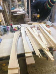 Joiner hand-crafting a bespoke timber sash window frame in the workshop